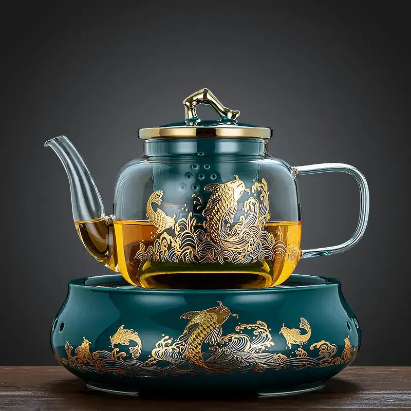 Glass teapot and ceramic warmer base in dark green with ornate gold koi fish design and gold lid handle.