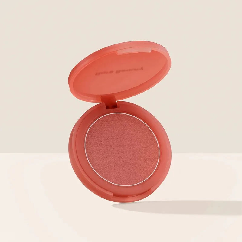 Rare Beauty powder blush in a coral-pink compact with a smooth, matte finish for vibrant cheek and lip makeup color.