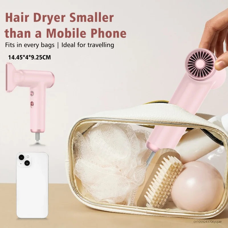 Pink portable mini hair dryer, high-speed brushless motor, compact travel size with nozzle attachment in a makeup bag.