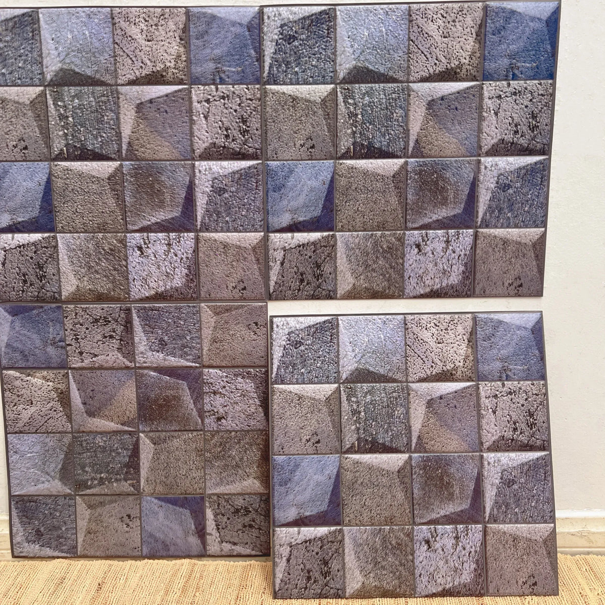 Purple-gray textured cube-pattern peel-and-stick tile sheets on a backing grid