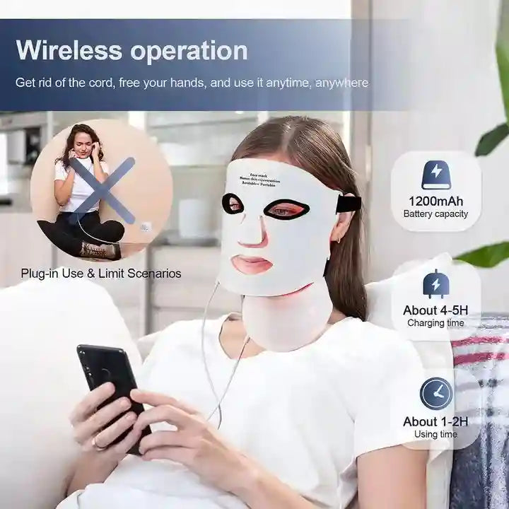 A woman wearing a flexible white silicone LED face and neck therapy mask while looking at her smartphone.