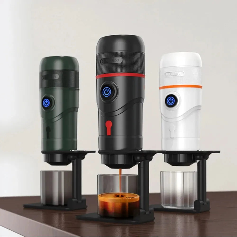 HiBREW portable espresso makers in green, black, and white on stands, with one brewing coffee into a glass cup.