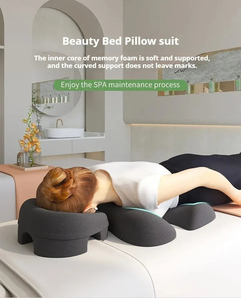 Dark grey memory foam massage pillow set for face and chest support on a spa treatment bed.