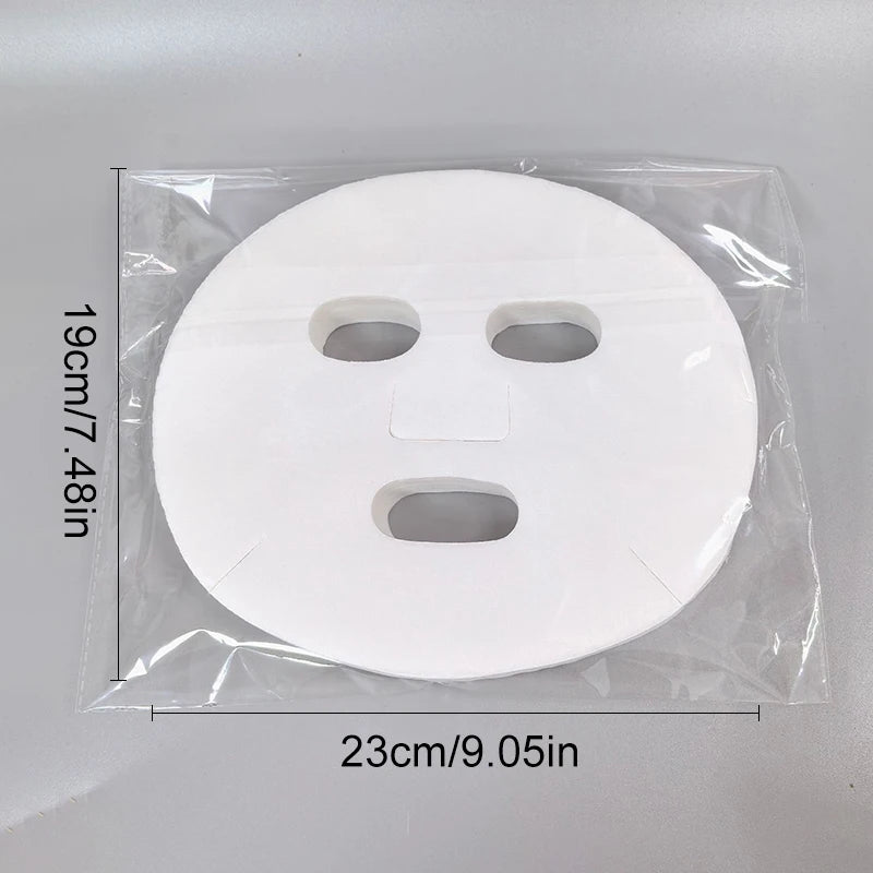 White, circular disposable facial mask sheet with cutout holes, inside a clear plastic bag with measurement labels.