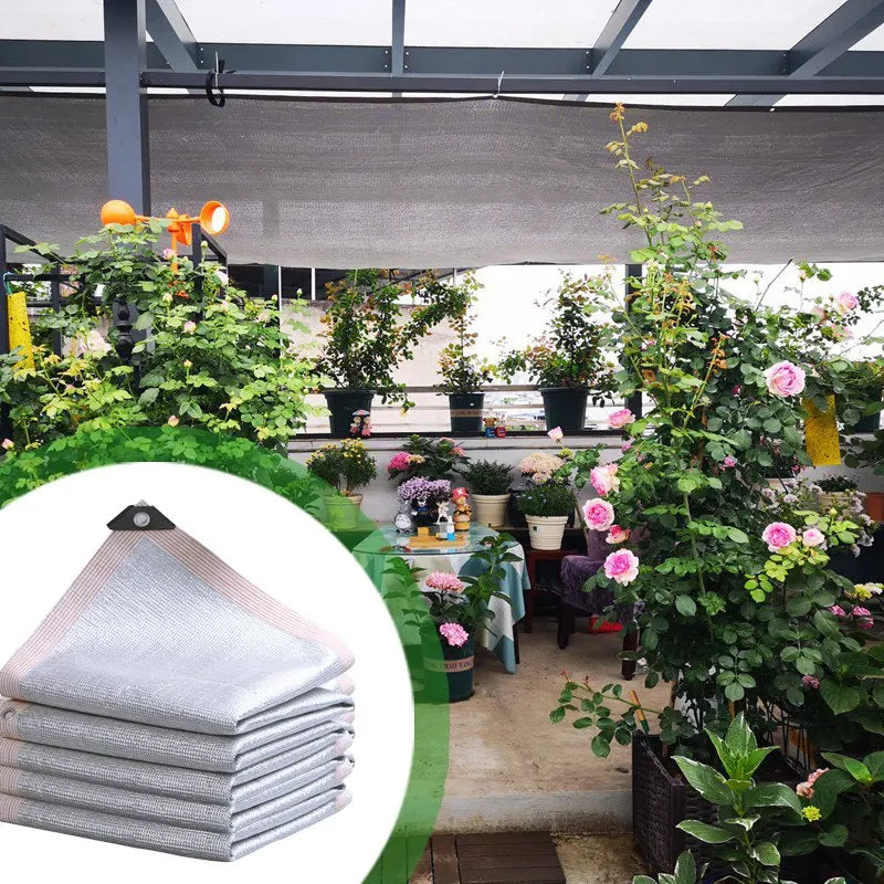 Stacked silver sunshade mesh sheets with corner grommet, shown for garden use