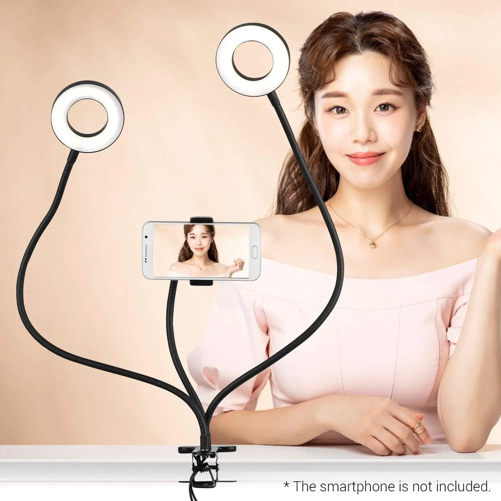 Dual ring light stand with flexible gooseneck arms and a central smartphone clamp for video recording and lighting.