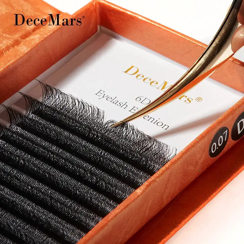Black 6D-W shaped eyelash extension strips inside an orange branded box, lifted by gold tweezers.