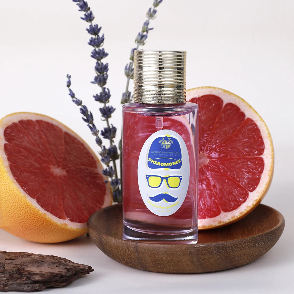 Luxury 50ml pink pheromone perfume spray bottle with gold cap, presented with fresh grapefruit and lavender sprigs.