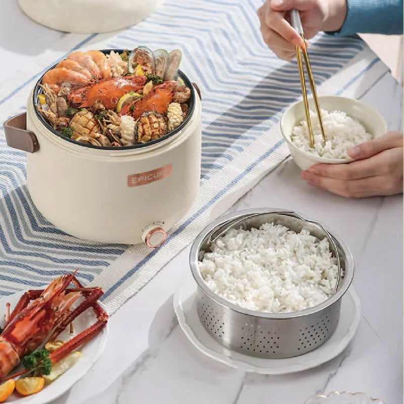 White mini electric cooker with steaming insert and rice bowl, lid open on countertop.