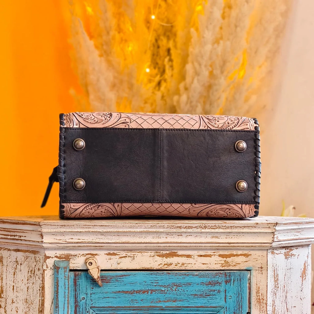 Luxury hand-tooled floral leather weekender trunk bag with black base, contrast stitching, and metal protective feet.
