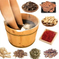 Legs soaking in wooden bucket with herbal foot bath bag, surrounded by natural Chinese medicine ingredients and herbs.