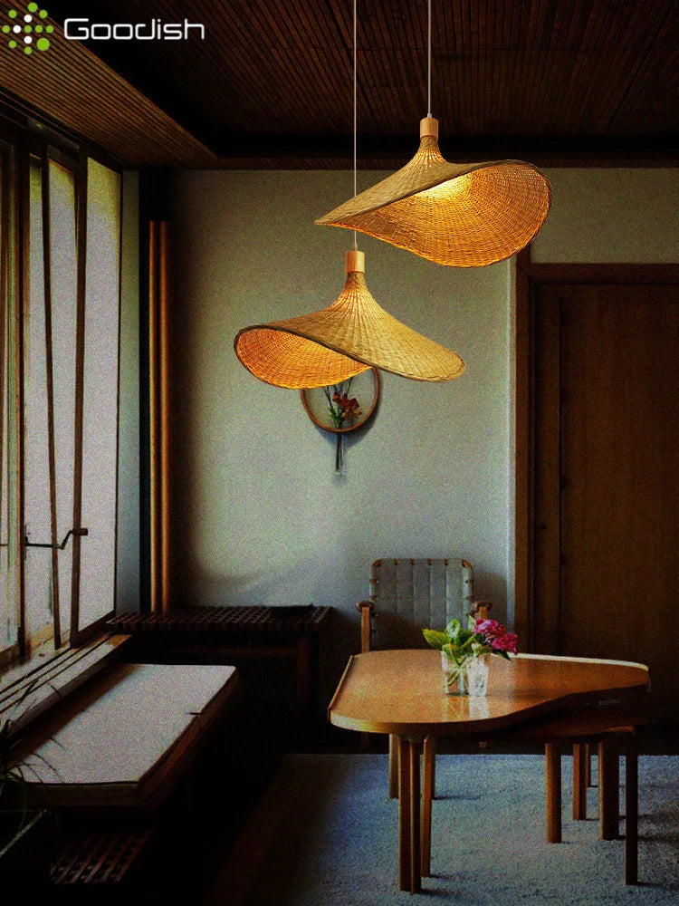 Two woven bamboo pendant lights with wide, undulating brims hanging above a wooden dining table in a cozy room.