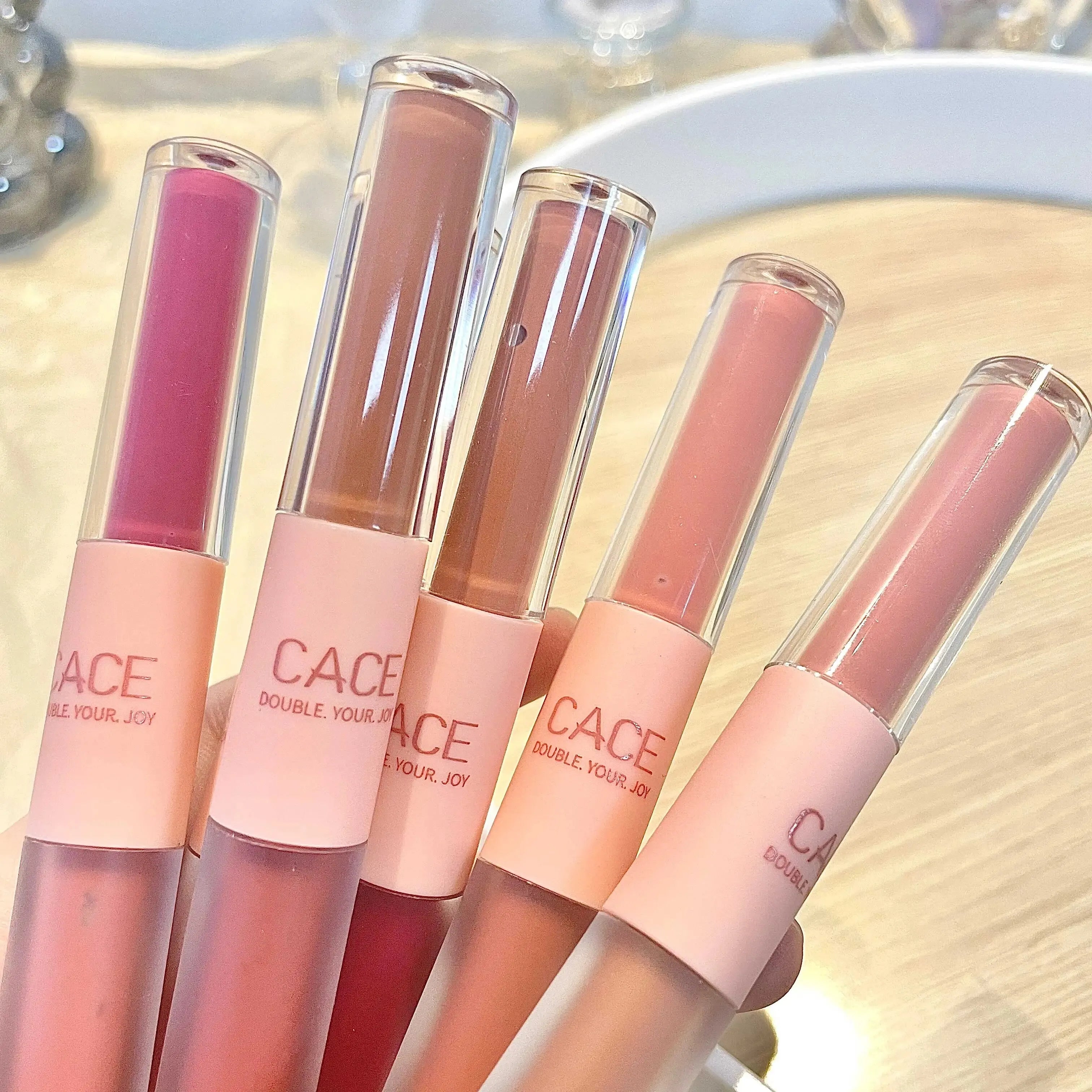 CACE double-head lip glosses in matte and water-gloss finishes, featuring a variety of nude and pink lip makeup shades.