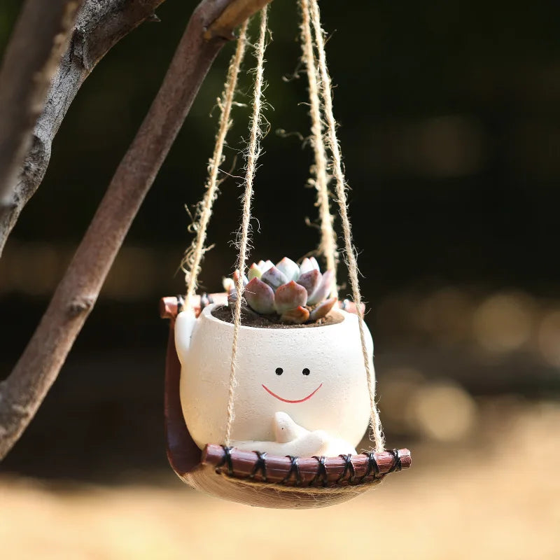 Mini hanging succulent planter with smiling face and small succulent in rope-hung pot