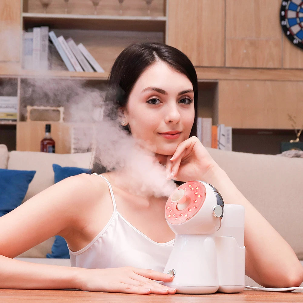 Small white and pink facial steamer with light therapy, emitting a steady stream of mist for skin care.