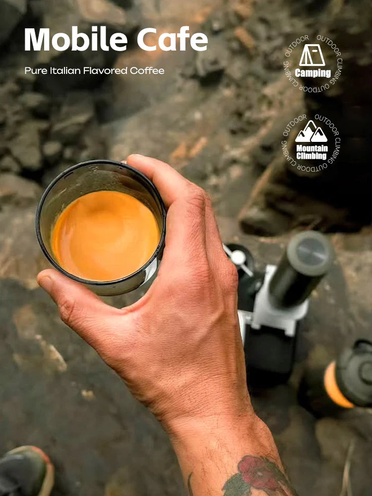 Hand holding a cup of espresso brewed by a compact, black and silver portable coffee maker for outdoor camping.