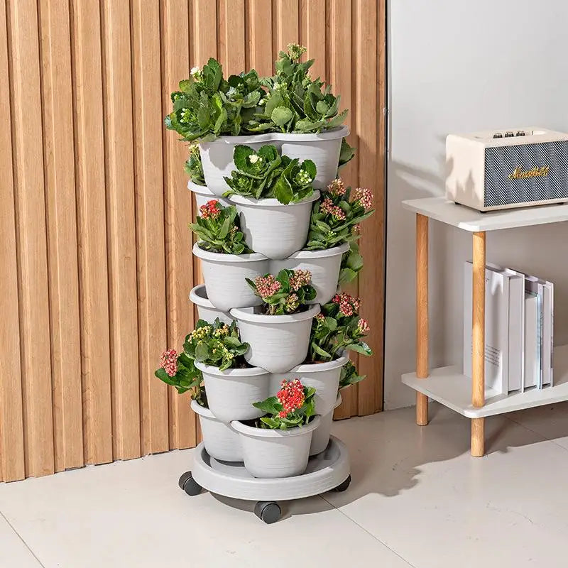 White stackable planter tower with green plants and small flowering clusters