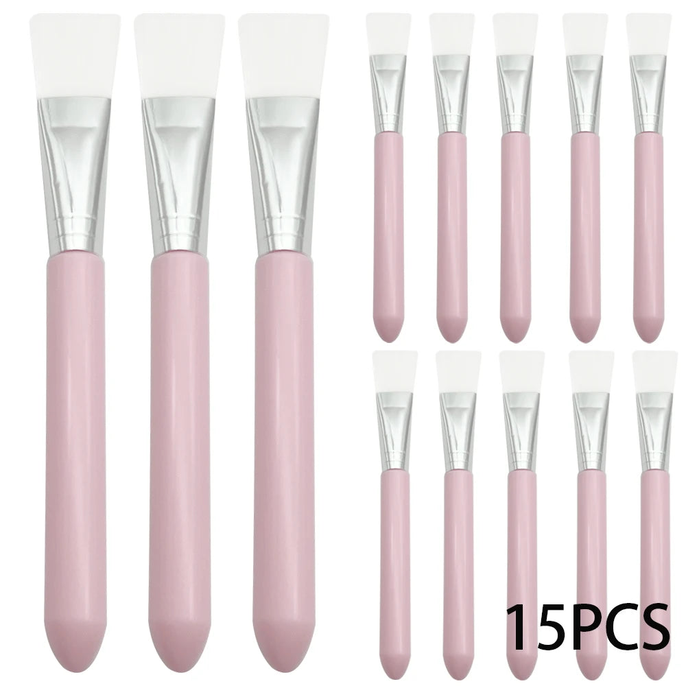 A set of 15 silicone facial mask brushes with white flat heads, silver ferrules, and smooth pastel pink handles.
