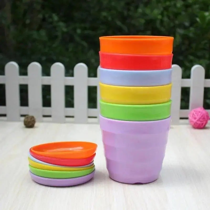 Stacked plastic plant pots with saucers in purple, orange, red, yellow, and green