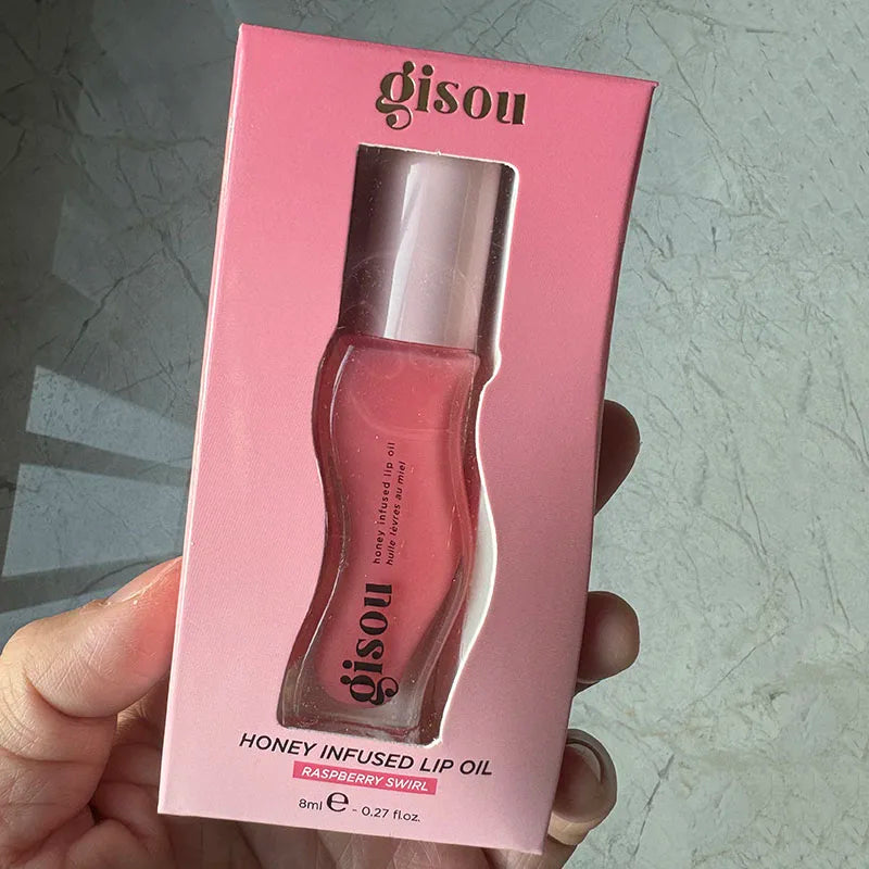 Gisou Honey Infused Lip Oil in Raspberry Swirl, a moisturizing, plumping glossy lip treatment in pink packaging.