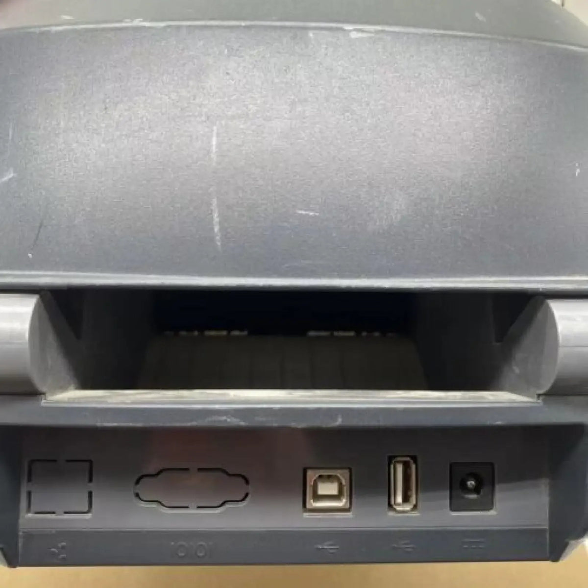 Barcode label printer part showing front ports and card slots, dark gray housing
