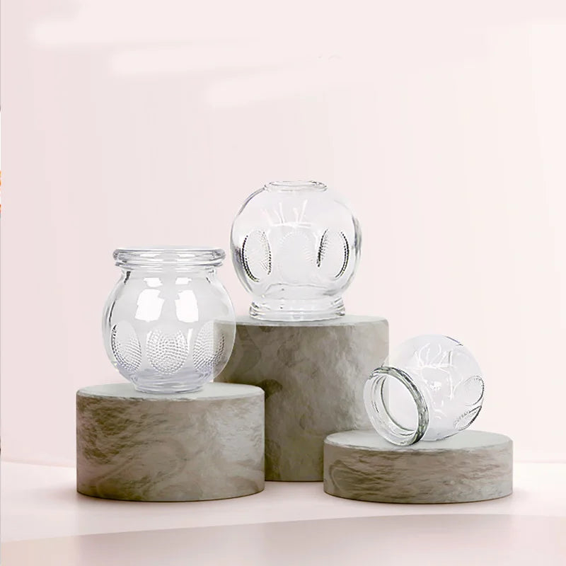 Extra thick clear glass cupping therapy set with textured grip for professional and home massage use on stone pedestals.