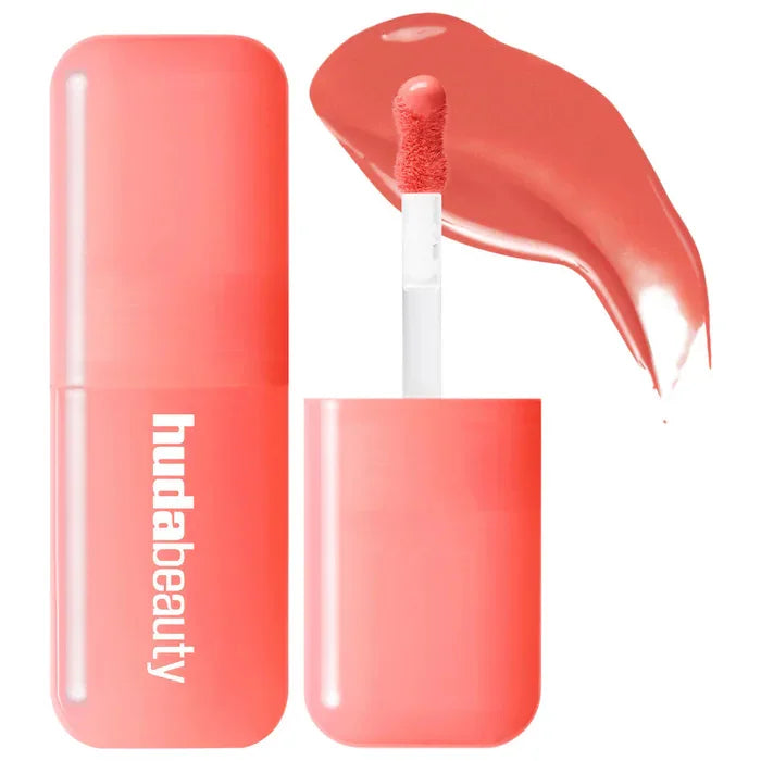 Huda Beauty coral hydrating lip and cheek tint stick with creamy texture and swatch applicator.