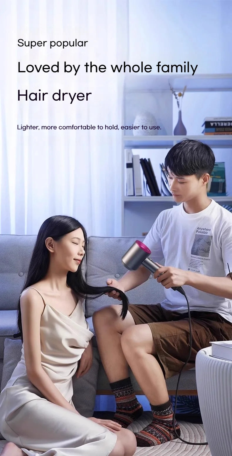 Man using a sleek, silver high-speed negative ion hair dryer with pink accents to dry a woman’s hair at home.