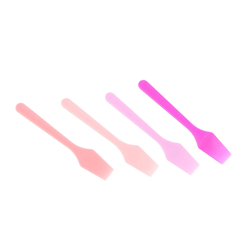 Four small, smooth plastic cosmetic spatulas in a gradient of pink shades, from light pastel to deep magenta.