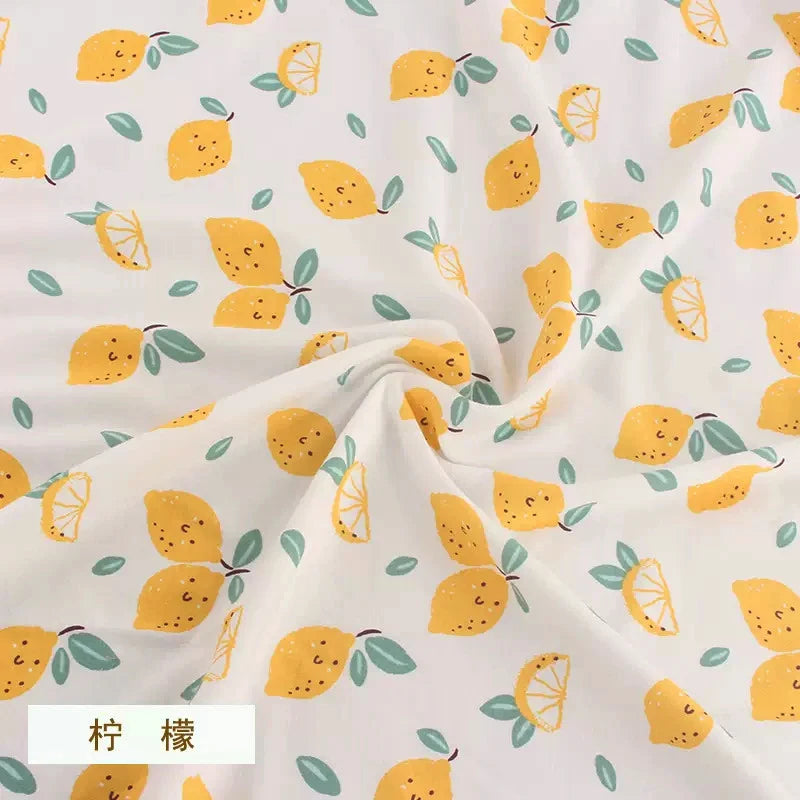 White Tidesmit knit fabric featuring a repeating cute yellow lemon and mint leaf pattern in a soft, draped texture.