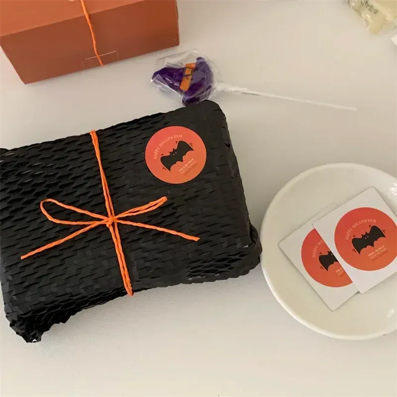 Custom circular seal stickers on black wrapped gifts, orange border and orange logo.