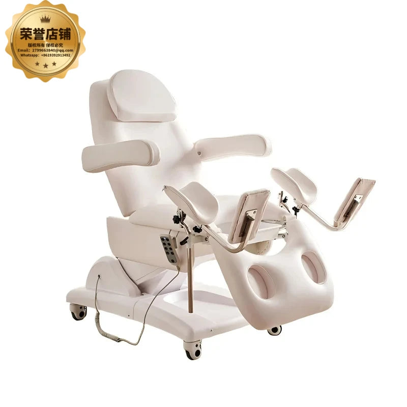 White electric medical examination chair with leg supports and remote control, used for gynecological procedures.