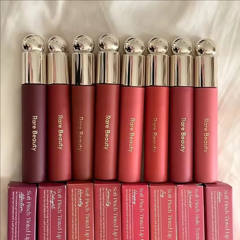 Rare Beauty Soft Pinch Tinted Lip Oil collection in various shades with moisturizing gel formula and metallic caps.