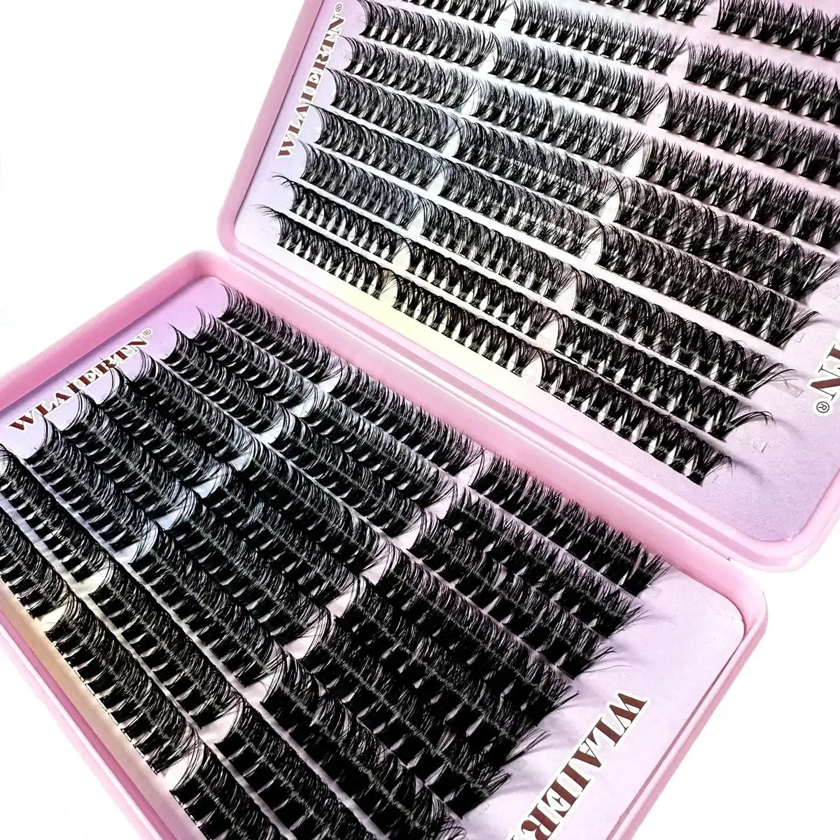 Black individual cluster eyelashes in a pink hinged tray for cosmetic eye makeup application.