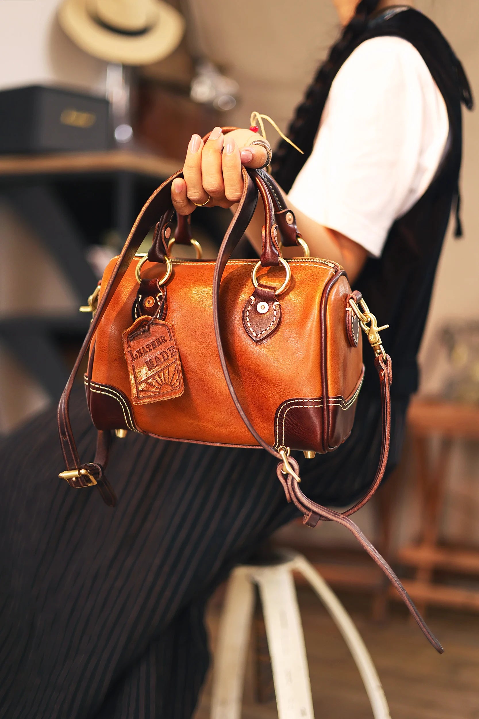 Small vintage designer handbag in tan cowhide leather with dark brown trim, brass hardware, and a branded leather tag.