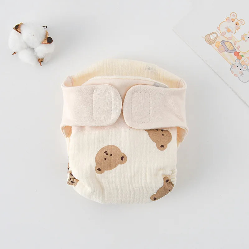 Cream baby care cloth diaper with cute bear pattern and Velcro closure.