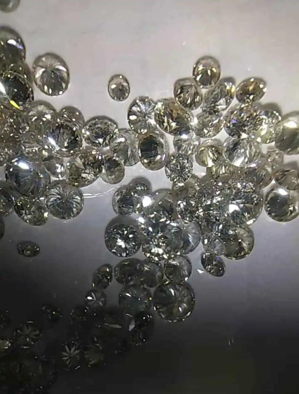 Loose round brilliant diamonds, white, scattered pile on light surface