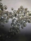 Loose round brilliant diamonds, white, scattered pile on light surface