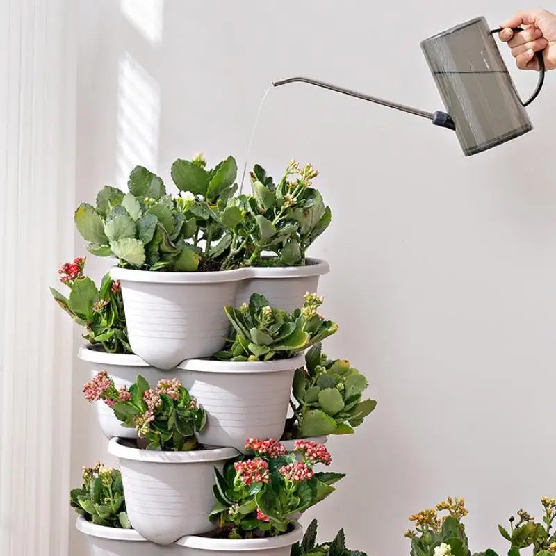 Stackable white planter tower being watered with a metal watering can
