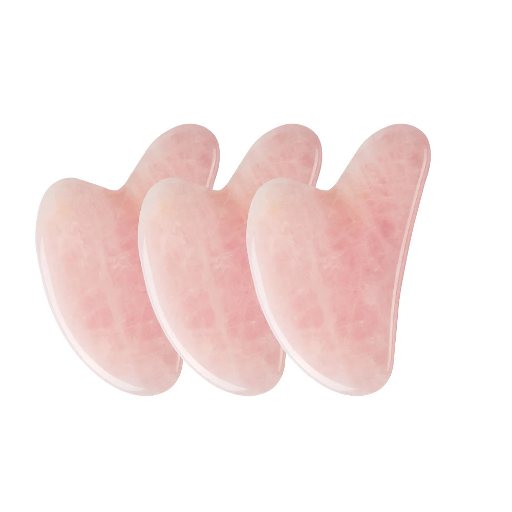 Three heart-shaped rose quartz gua sha facial massage tools with a smooth, polished stone texture.