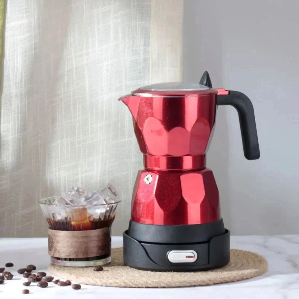 Electric red aluminum moka pot on black base next to a glass of iced coffee and coffee beans on a table.