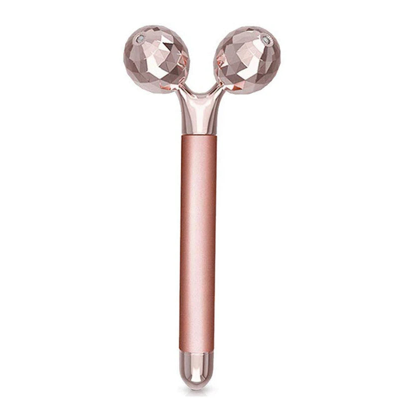 Rose gold electric face massager with two faceted, spherical rollers on a sleek, matte cylindrical handle.