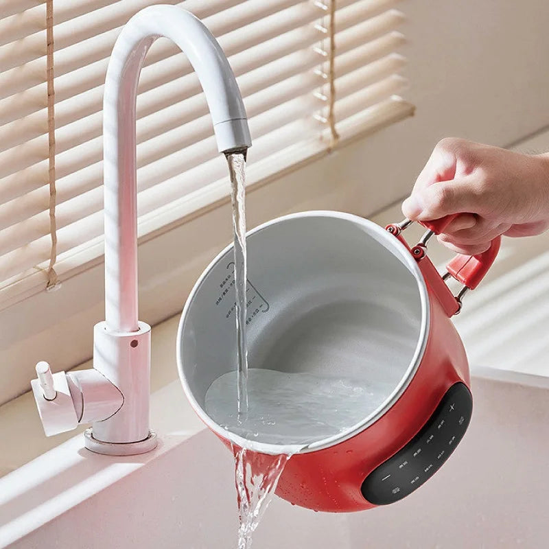 Red electric cooking pot being filled; inner stainless pot visible through open top