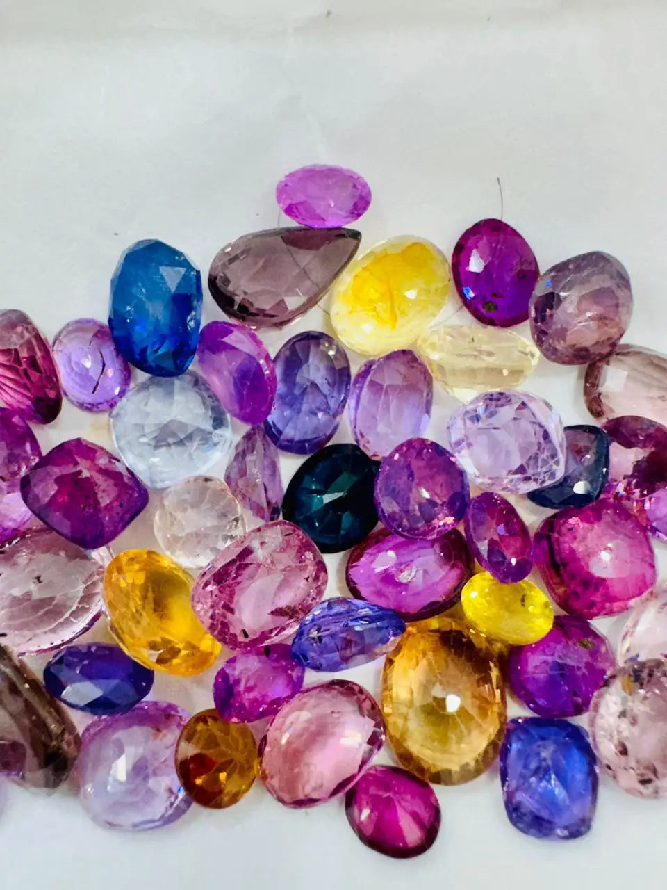 Loose multicolor sapphire gemstones pile of faceted oval and round stones