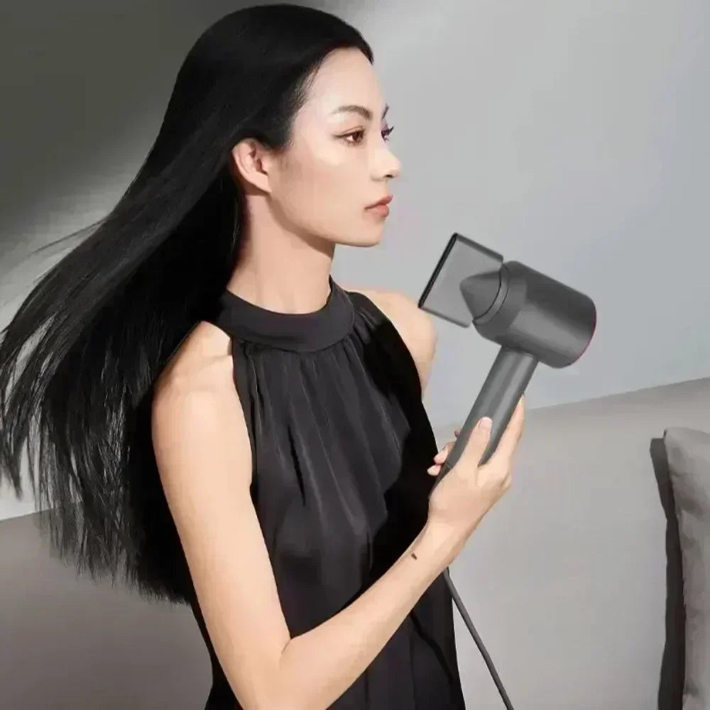 Woman using a sleek grey 5-in-1 professional hair dryer with styling nozzle for smooth, salon-quality hair results.