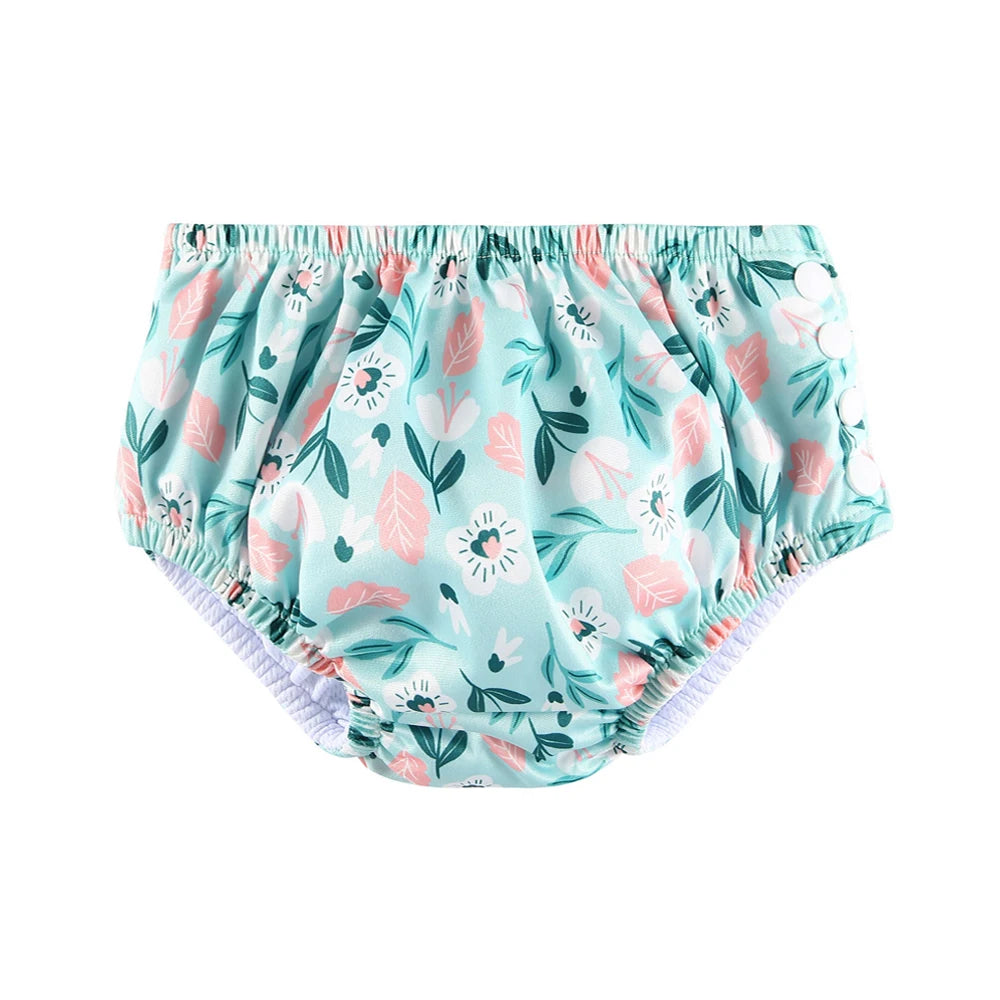 Reusable baby swim diaper with teal, pink, and white floral print and snap-side closure for infant swim care.