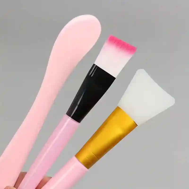 A pink spatula, a soft-bristled brush with a pink tip, and a white silicone applicator brush with a gold handle.