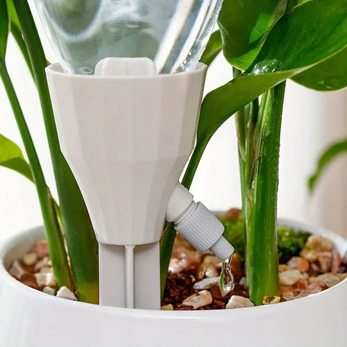 White drip irrigation plant sprinkler attachment with adjustable flow nozzle near pot soil.