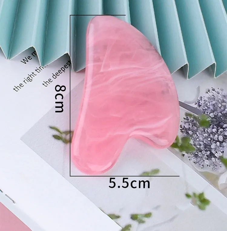 Pink resin gua sha tool with a marbled finish, heart-shaped design, measuring 8cm by 5.5cm.