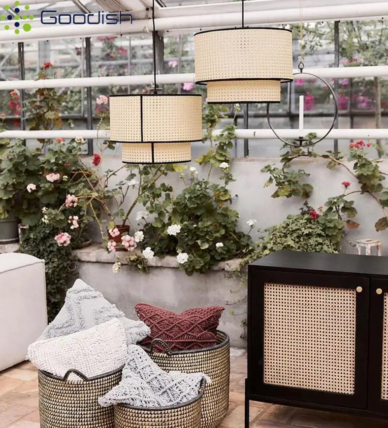 Two-tiered cylindrical pendant lights made of natural woven rattan with black trim, hanging in a greenhouse setting.
